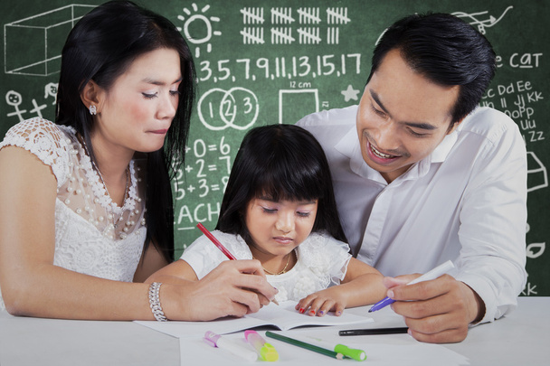 Маленькая девочка учится с родителями в классе
 - Фото, изображение