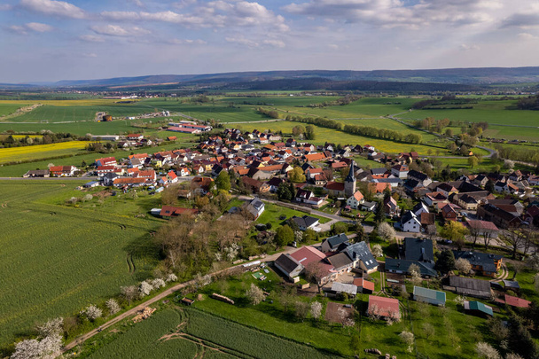 Vesnice obklopená krásnou kopcovitou zelenou krajinou za barevného východu slunce, letecké záběry. Německo. - Fotografie, Obrázek