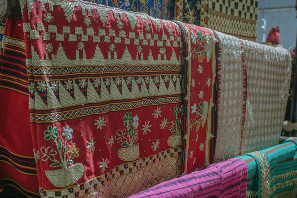 Kumaş çeşitliliği. Raflarda farklı kumaşlar sergileniyor. Endonezya 'nın Lampung eyaletinden tipik tapis kumaşı olarak adlandırılabilecek bir kumaş.. - Fotoğraf, Görsel