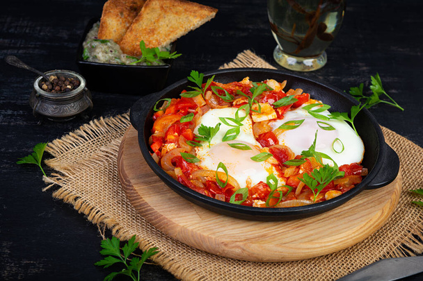 Shakshuka met gegrild brood. Gebakken eieren met tomaat, peper, knoflook en kruiden - Foto, afbeelding