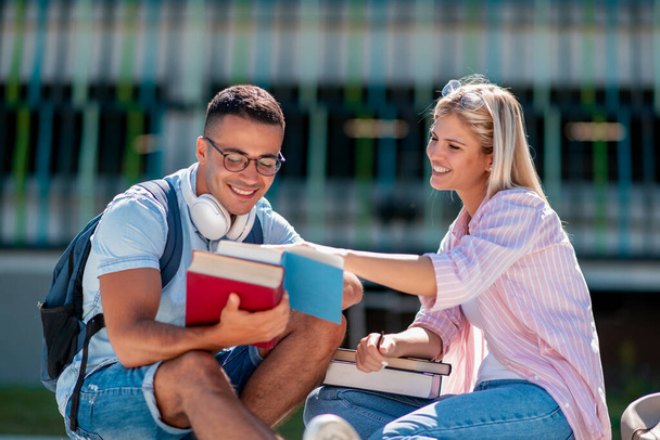 Portrait de couple en plein air avec des livres, assis sur le banc et apprenant ensemble. - Photo, image