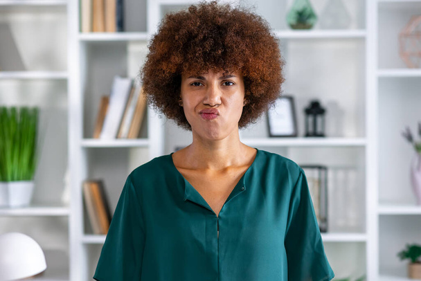Jovem mulher afro-americana ofendida olhando para a câmera depois de bullying ou insulto ou intolerância fica no escritório - Foto, Imagem