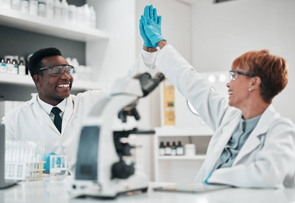 Scientist man, woman and high five in lab, smile or partnership with goals, results or innovation in workplace. African science expert, teamwork and congratulations for success with medical research. - Photo, Image