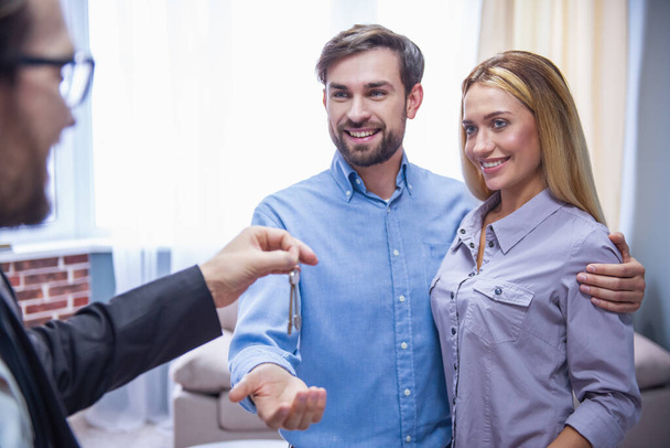Beau couple prend les clés de l'agent immobilier et sourire
 - Photo, image