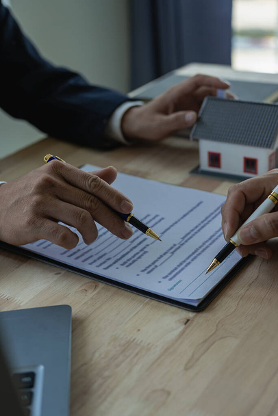 Emlakçı ev satın alma sözleşmesinin şartlarını tartışır ve müşteriden sözleşmeye yasal olarak girmek için belgeyi imzalamasını ister. dikey resim - Fotoğraf, Görsel