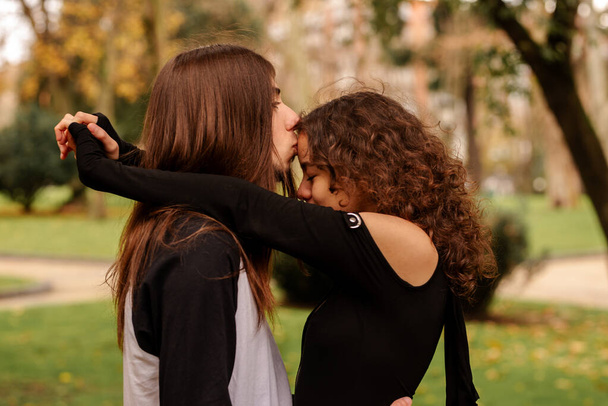 Альтернативно выглядящая гетеросексуальная пара обнимается и целуется в парке осенью. Соучастие в паре. любовь и единство - Фото, изображение