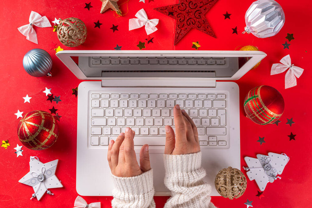 Kerst Nieuwjaar achtergrond met witte laptop toetsenbord en wintervakantie decor, ornamenten, op felrode achtergrond. Kerst online winkelen, voorbereiding op vakantie, bovenaanzicht kopieerruimte - Foto, afbeelding