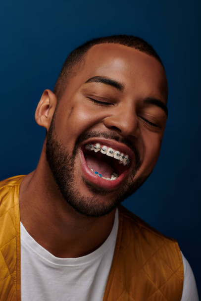 cheerful young man with beard and braces laughing with closed eyes at camera, fashion concept - Fotografie, Obrázek