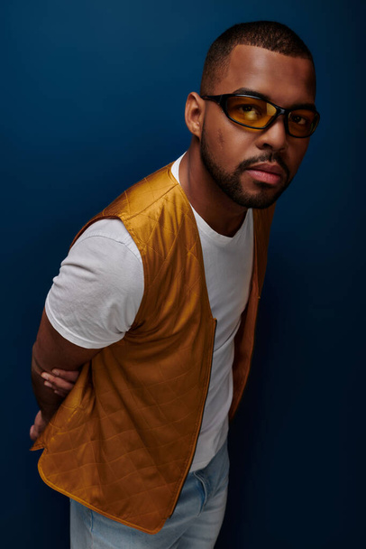 stílusos afro-amerikai férfi sárga mellény és napszemüveg néz kamera, divat koncepció - Fotó, kép
