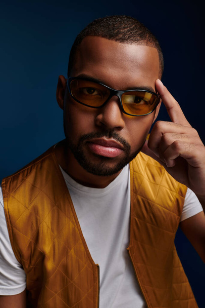 πορτρέτο του νεαρού άνδρα σε γυαλιά με γενειάδα και δάχτυλο κοντά στο πρόσωπο κοιτάζοντας κάμερα, έννοια της μόδας - Φωτογραφία, εικόνα