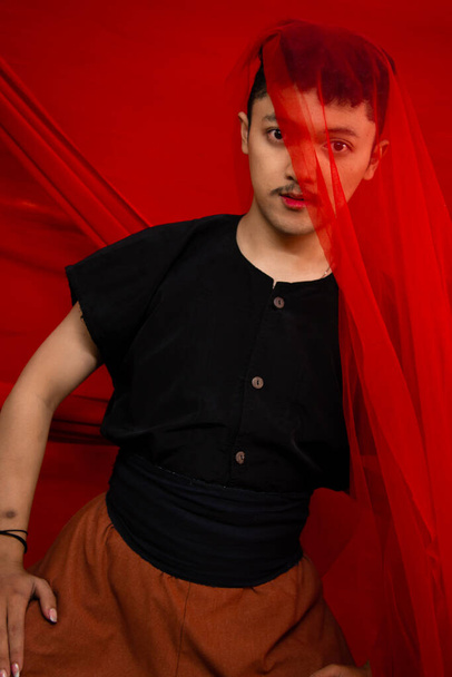 an Asian man standing in front of a red cloth with a red cloth hanging over his head during the day - Zdjęcie, obraz