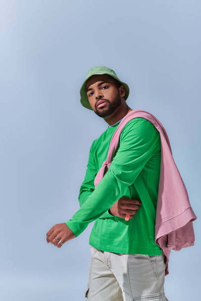 schöner trendiger Mann in grünem Sweatshirt und Panama, der aktiv vor der Kamera posiert, Modekonzept - Foto, Bild