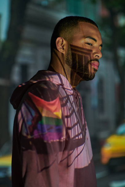 modèle masculin afro-américain à la mode posant de profil dans des projecteurs numériques, concept de mode - Photo, image