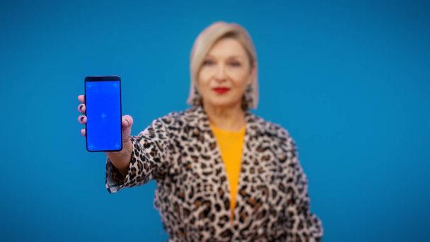 A smartphone with a pre-keyed screen is being held by a mature woman, discounts and sales, mobile banking - Fotoğraf, Görsel
