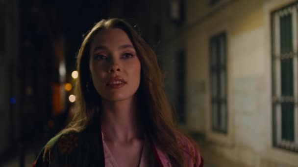 Lady walking dark street enjoying empty night town close up. Portrait of attractive young woman strolling city late evening alone. Luxurious relaxed model looking camera with smile. Urban leisure. - Footage, Video