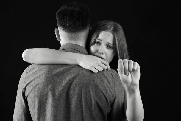 Siniaki na młodej kobiecie z mężem pokazującym pięść na ciemnym tle. Koncepcja przemocy domowej - Zdjęcie, obraz