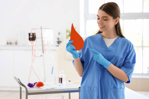 Enfermeira apontando para gota de sangue de papel na clínica - Foto, Imagem