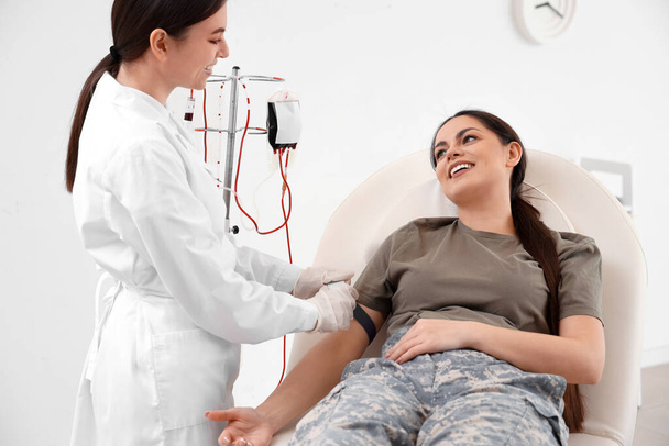 Médico preparando soldado femenino para transfusión de sangre en clínica - Foto, imagen