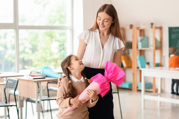 gelukkig klein meisje met roze school kegel en leraar in klas - Foto, afbeelding