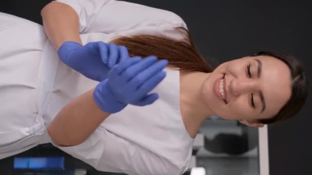 Mooie vrouwelijke arts draagt blauwe rubberen handschoenen. Gezondheidszorg concept. Verticale video. - Video