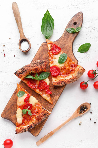 Tabla de madera con rodajas de sabrosa pizza Margarita y tomates frescos sobre fondo blanco - Foto, Imagen