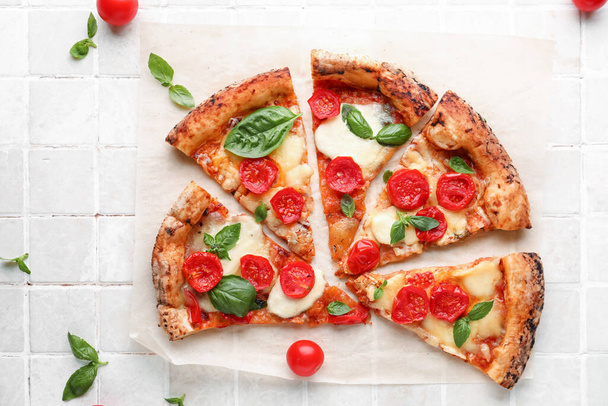 Rodajas de sabrosa pizza Margarita y tomates frescos sobre fondo beige azulejo - Foto, Imagen