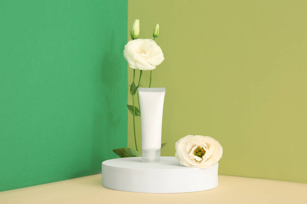 Composición con tubo de producto cosmético, podio de yeso y hermosas flores de eustoma sobre fondo de color - Foto, imagen