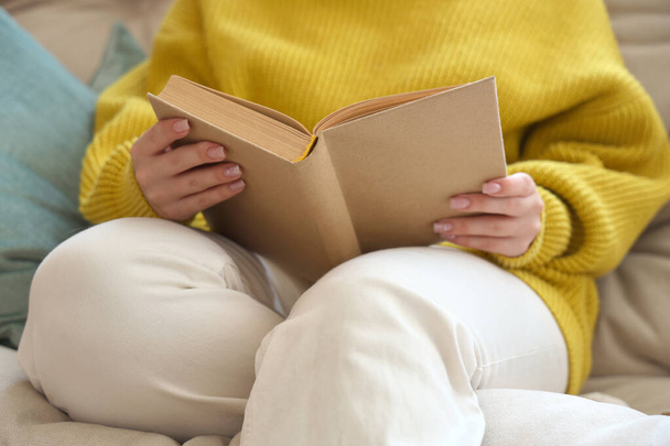 Junge Frau liest Buch auf Couch zu Hause, Nahaufnahme - Foto, Bild