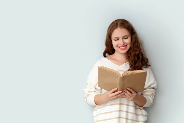 Young woman reading book on light background - Photo, Image