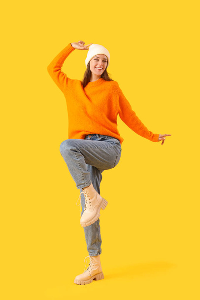Felice giovane donna in abiti invernali su sfondo giallo - Foto, immagini