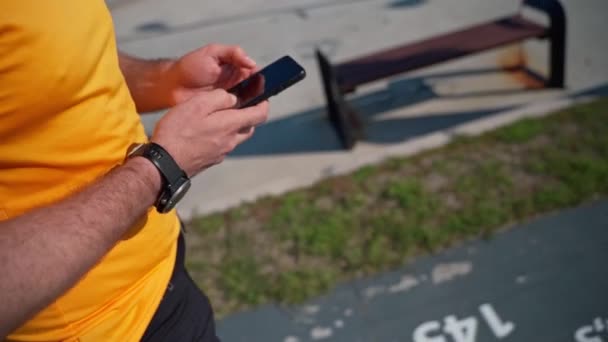 Lähikuva Lenkkeily mies käyttää älypuhelinta jälkeen käynnissä urheilutoimintaa. Mafiasovellus, jäljitin, nopeus, syke. Juoksija aikuinen harjoittelun jälkeen matkapuhelimen urheilullisilla sovelluksilla - Materiaali, video