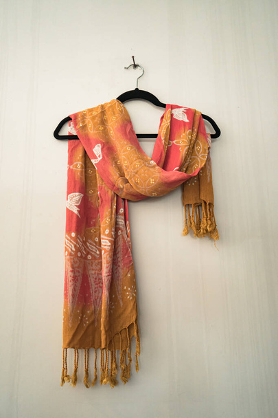 Traditional Javanese batik motif scarves with delicate details hang on a white wall. This scarf with batik motifs is hand-drawn by professional craftsmen with various motifs and colors - Photo, Image
