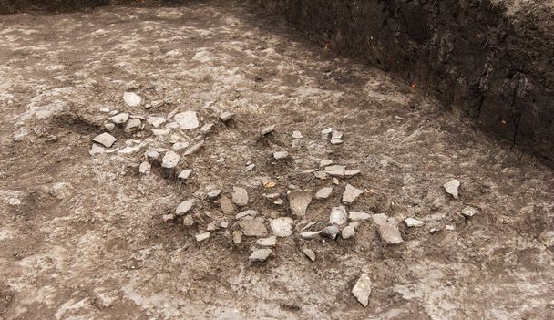 Archäologische Arbeiten, ausgegrabene Schindeln, Stücke antiken Tonartefakts, Gefäße in Lehmboden, Hintergrund - Foto, Bild