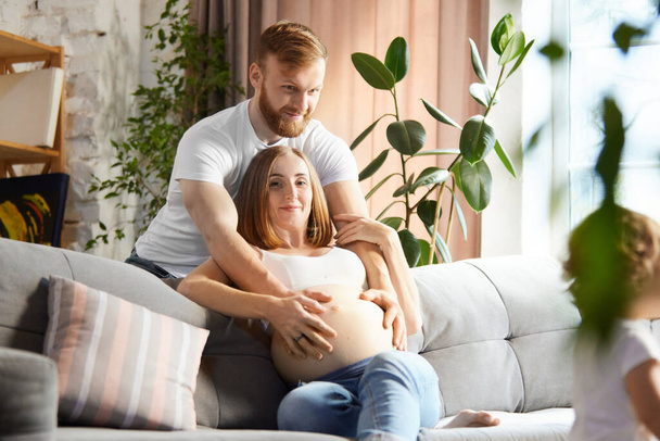Support and care. Loving man, husband holding hand on his wife belly. Couple spending time at home together. Concept of pregnancy, family, love, relationship, parenthood and childhood - Φωτογραφία, εικόνα