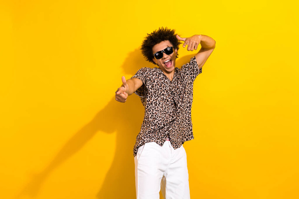 Photo of positive confident guy with afro hair dressed print shirt in sunglass indicating at you isolated on yellow color background. - Foto, afbeelding