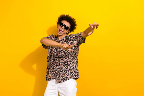 Photo of positive crazy guy with afro hair dressed print shirt in sunglass dancing scream yeah isolated on yellow color background. - Foto, immagini