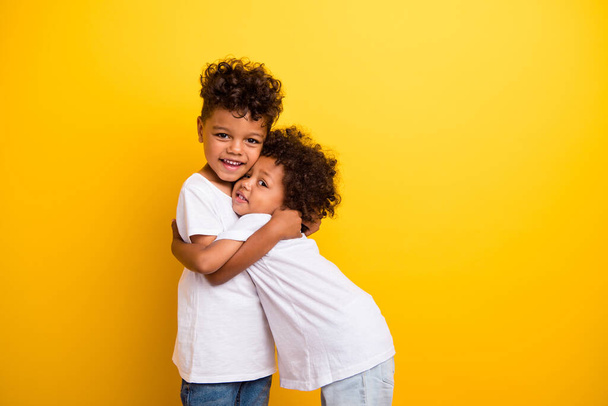 Photo of two friendly cheerful little brothers cuddle have good mood empty space isolated on yellow color background. - Foto, immagini