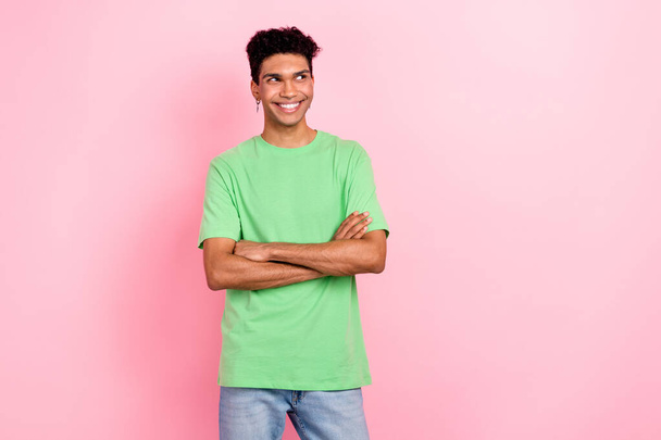 Фото задумчивого мечтательного мужчины, одетого в зеленую футболку, сложенные руки, выглядящие пустым изолированным розовым цветом фона.. - Фото, изображение