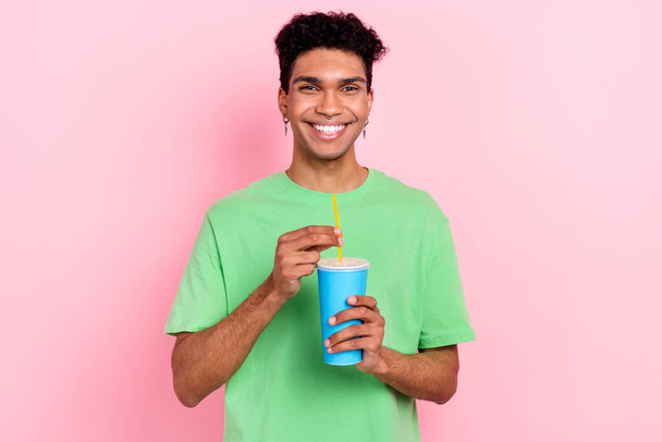 Photo of cheerful positive guy wear green t-shirt enjoying tasty cold beverage isolated pink color background. - Foto, Imagen