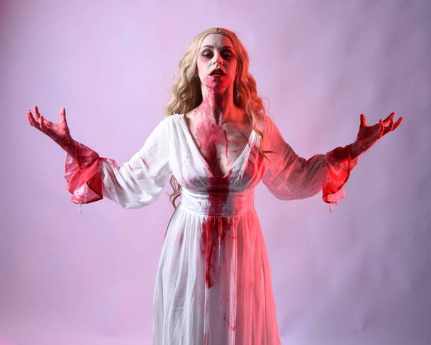 Primer plano retrato de la novia vampiro miedo usando elegante disfraz de fantasía halloween salpicadura sangrienta. Aislado en el fondo del estudio con las manos gestuales extendiéndose hacia la cámara. - Foto, Imagen