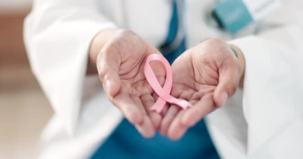 Dłonie, medyczna i różowa wstążka na raka piersi z lekarzem w szpitalnym zbliżeniu dla wsparcia lub empatii. Opieka zdrowotna, nadzieja i miesiąc świadomości z pewnym profesjonalistą medycyny w klinice. - Materiał filmowy, wideo