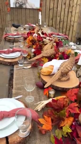 Pöydällä on lautasia puisilla telineillä haarukoiden vieressä veitset ja lasit Kuivat punaiset ja mustat maissinpunaiset lautasliinat keskellä kaikki on valmis päivälliselle Halloween-syksyllä lokakuu-iltana.  - Materiaali, video