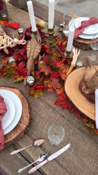 On table there are plates on wooden stands next to forks knives and glasses Dry heads of red and black corn red napkins in middle everything is ready for dinner on Halloween autumn October evening  - Footage, Video