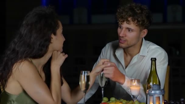 Young man and woman talking and clinking glasses with champagne while having date outdoors in the evening. Romantic date on the roof. Romantic concept. Couple in love. Real time - Footage, Video