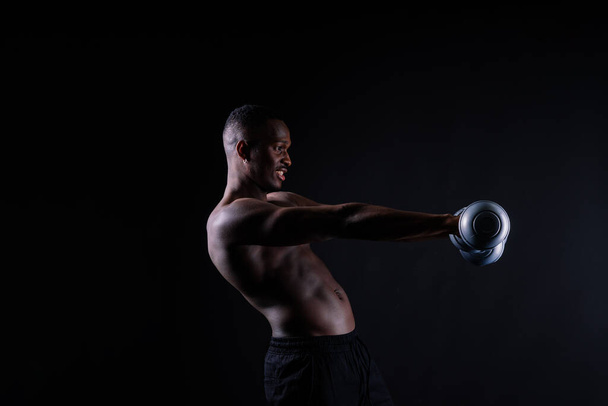 Спортсмен виконує вправи за руку з гантелями. М'язова фітнес-модель сила і мотивація. - Фото, зображення