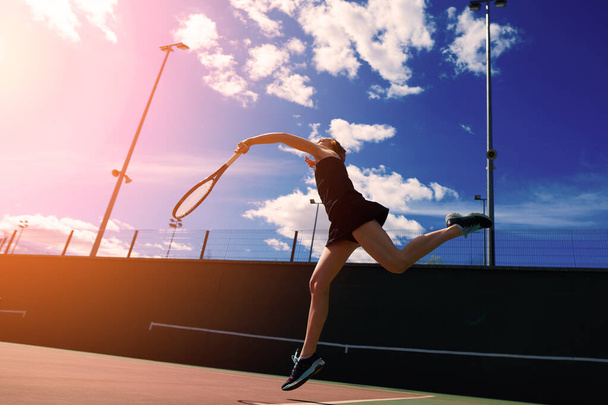 Сексуальная теннисистка в белом платье и на каблуках держит теннисную ракетку на корте. Молодая женщина играет в теннис, спорт - Фото, изображение