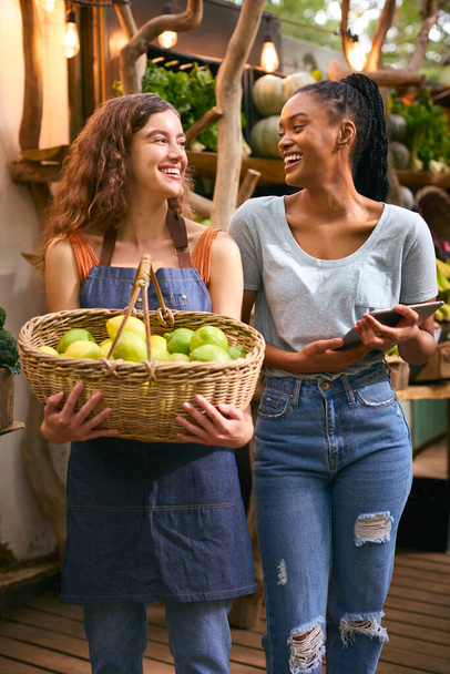 Две женщины с корзиной лимонов и цифровой планшет работает на рынке фруктов и овощей - Фото, изображение