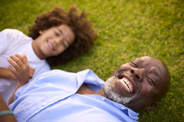 Overhead Portrait Shot Of Loving Grandfather And Grandson Lying On Grass Laughing Together - Valokuva, kuva