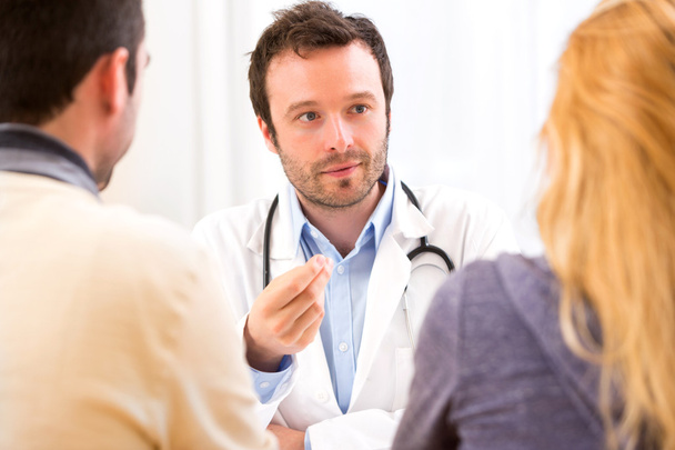 Young attractive doctor advising a young couple of patients - Foto, Bild