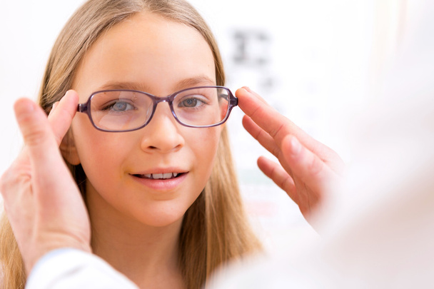 Young little girl trying glasses at the optician - Foto, Bild